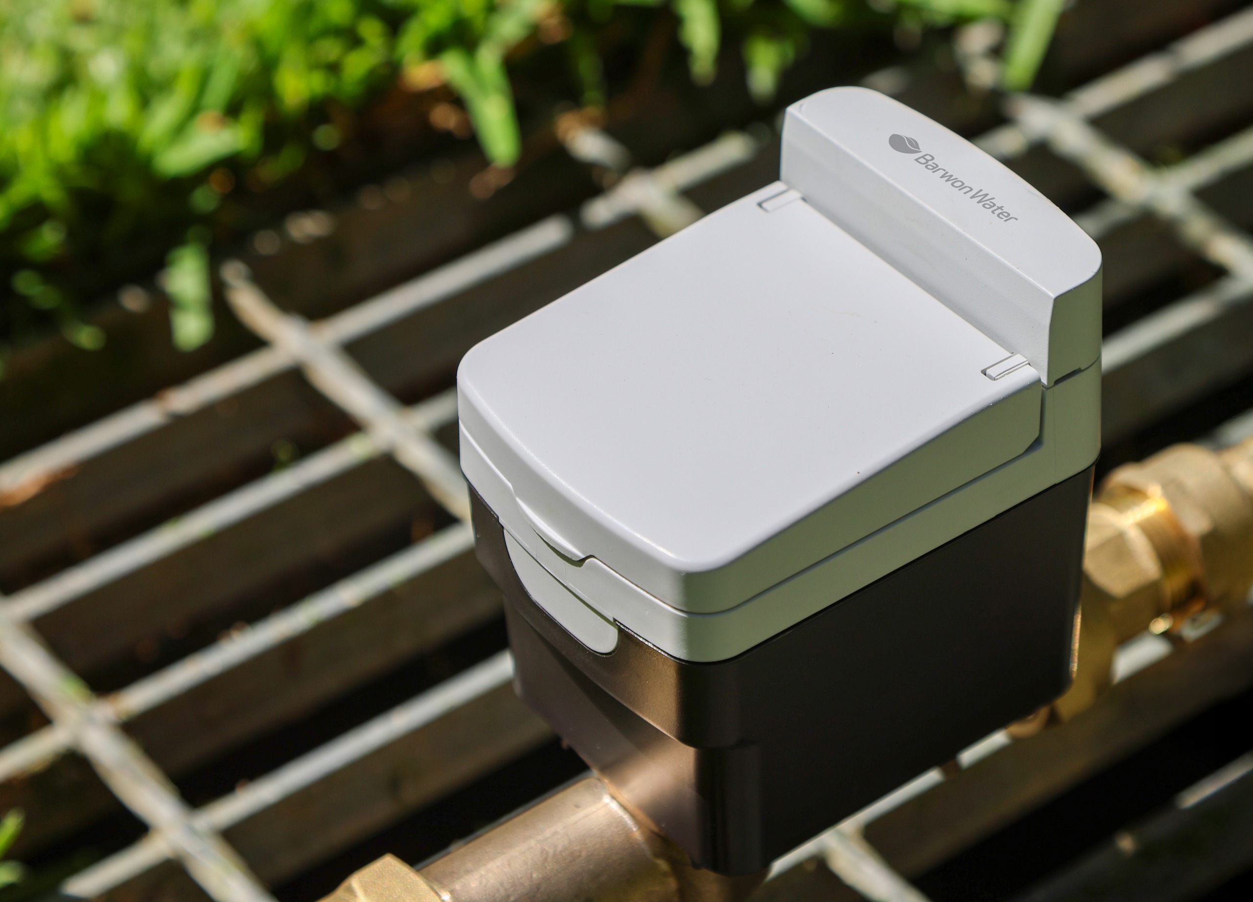 A digital meter on a grate with green grass in the background.